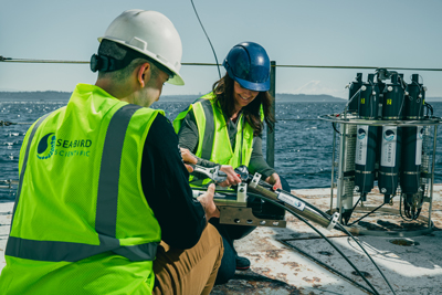 Two oceanographers using a wrench to set up an instrument