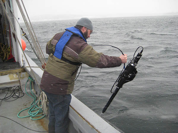 A scientist using a device to measure ocean carbon on a boat in the ocean