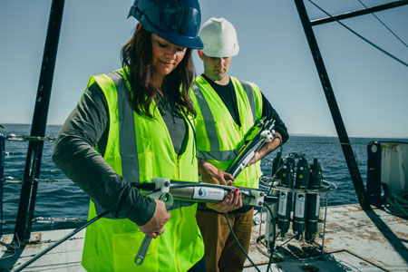 Two oceanographers using a wrench to set up an instrument